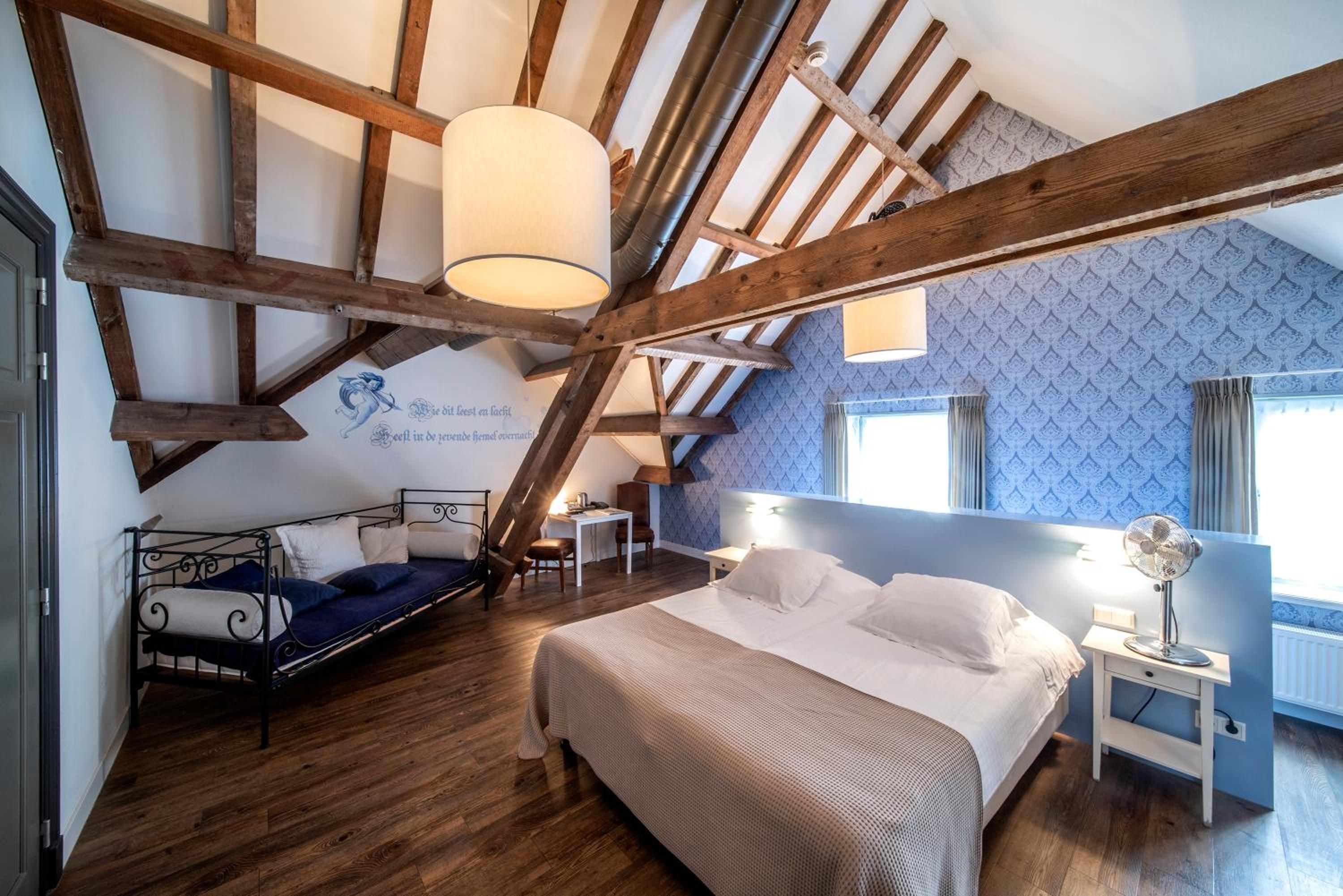 Ein Schlafzimmer mit schrägem Dach, einem Bett, einem Schreibtisch und einem Stuhl.