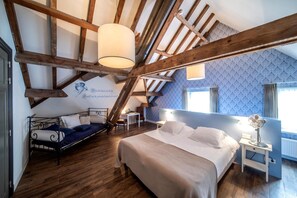 A bedroom with a sloped ceiling, a bed, a desk, and a chair. - Herberg De Brabantse Kluis (Aarle-Rixtel)