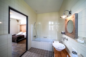A modern bathroom with a bathtub, a sink, and a mirror. - Herberg De Brabantse Kluis (Aarle-Rixtel)