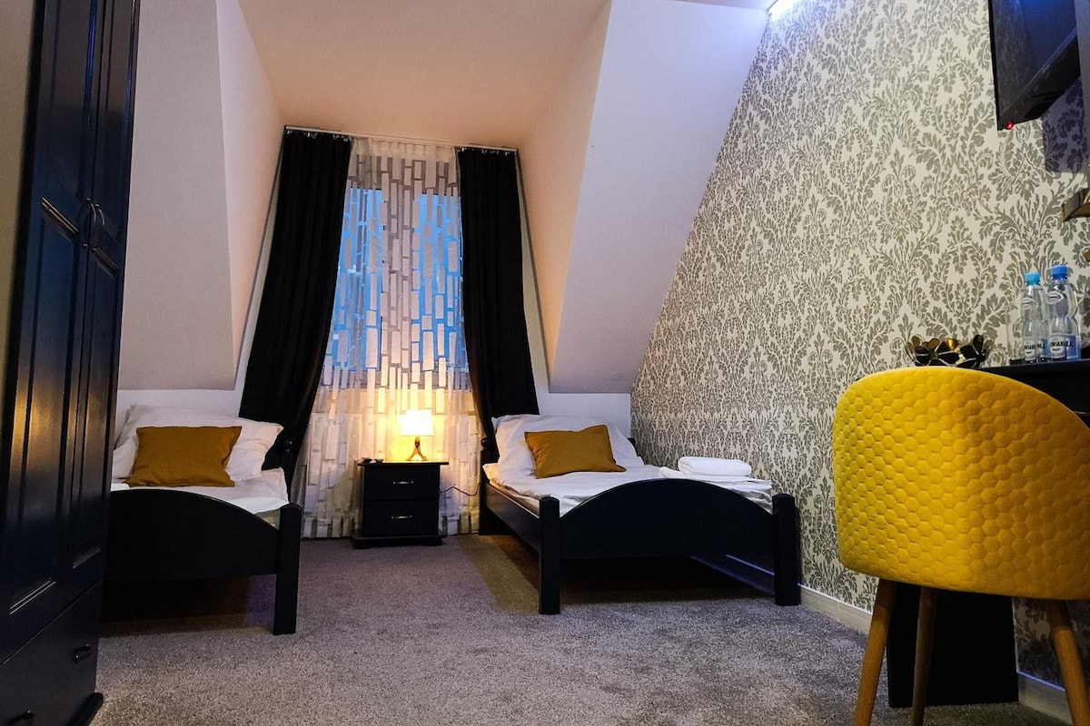 Un dormitorio con dos camas, una mesita de noche, una lámpara, una silla y un televisor.