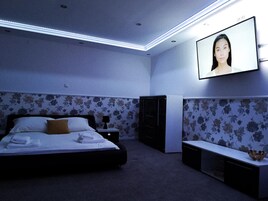 Un dormitorio con una cama, televisor montado en la pared, cómoda y un banco.