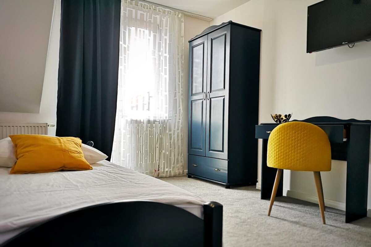 Un dormitorio con cama, armario, escritorio y silla.