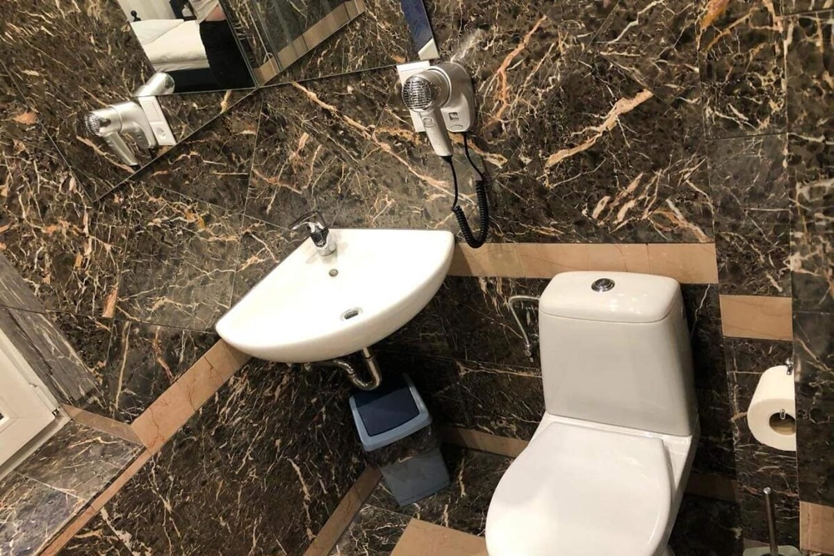 A bathroom with a white sink, toilet, and a mirror.