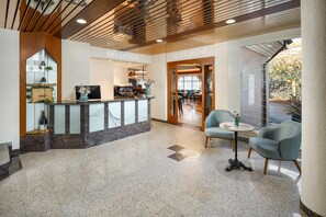 A reception area with a counter, seating, and a view of the outside. - Hotel An Der Reuss (Gisikon)