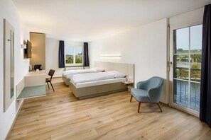 A modern hotel room with a large bed, a seating area, a desk, and a view of the outdoors. - Hotel An Der Reuss (Gisikon)