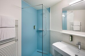 A modern bathroom with a glass shower enclosure, a white sink, and a mirror above the sink. - Hotel An Der Reuss (Gisikon)
