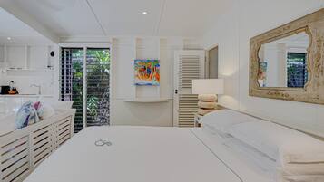 A hotel room with a bed, a bathroom, a painting, and a view of greenery.