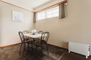 A dining area with a table and chairs, a radiator, and a window with curtains.