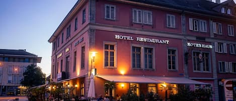 Restaurante de hotel con terraza y fachada roja.