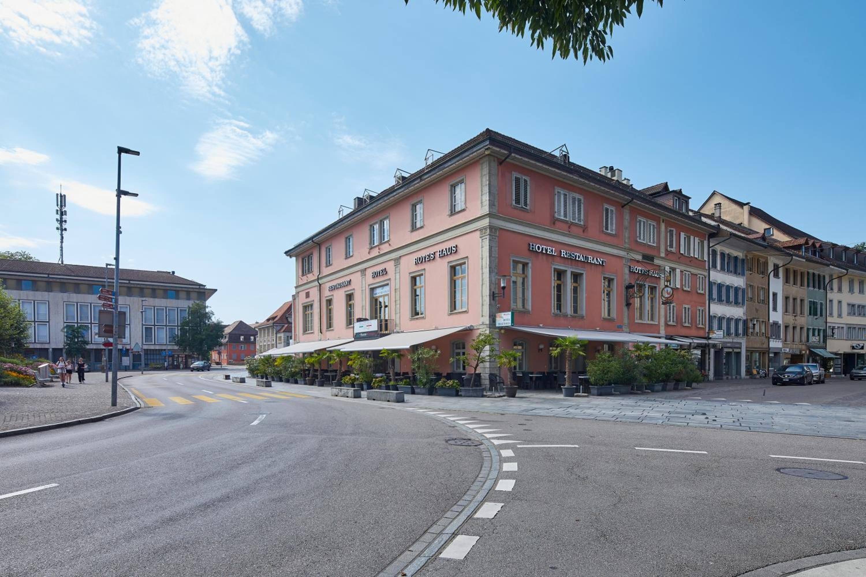 A hotel with a restaurant on the ground floor, featuring a red facade and a white awning.
