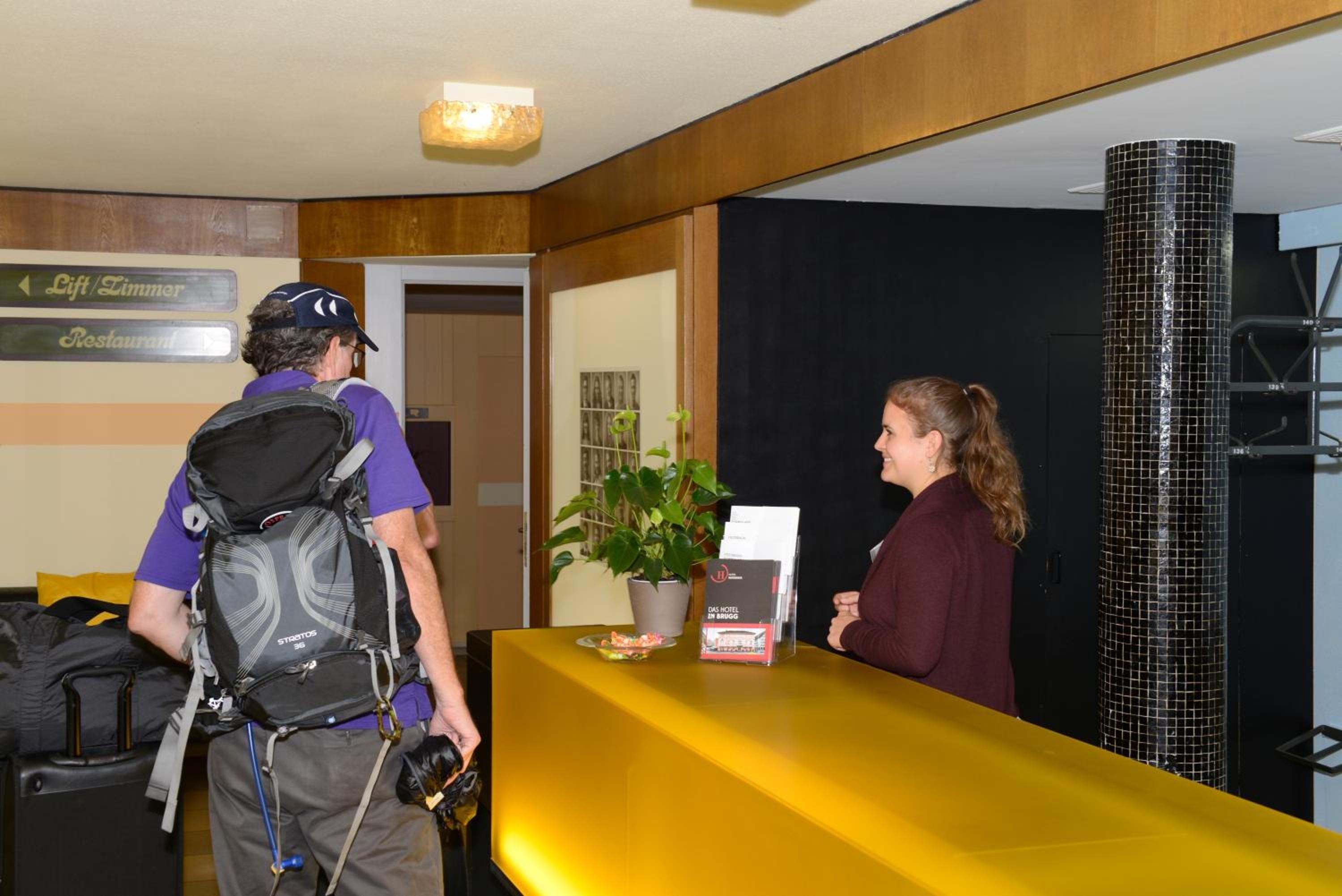 A hotel reception desk with a sign indicating the direction to the lift/limmer and restaurant.