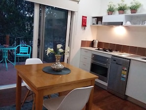 Una cocina con mesa, sillas, estufa, horno y lavavajillas.