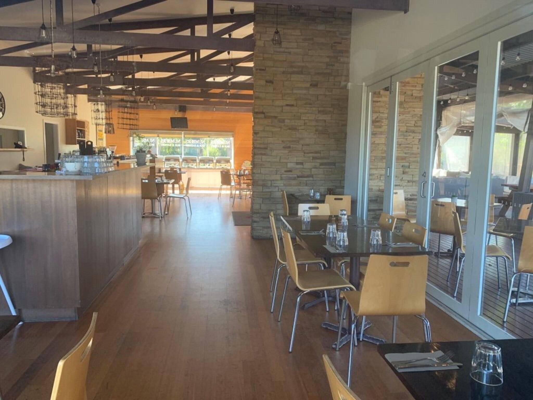A spacious cafe with a long counter, multiple tables, and chairs.