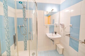 Un baño con ducha, lavabo y espejo.