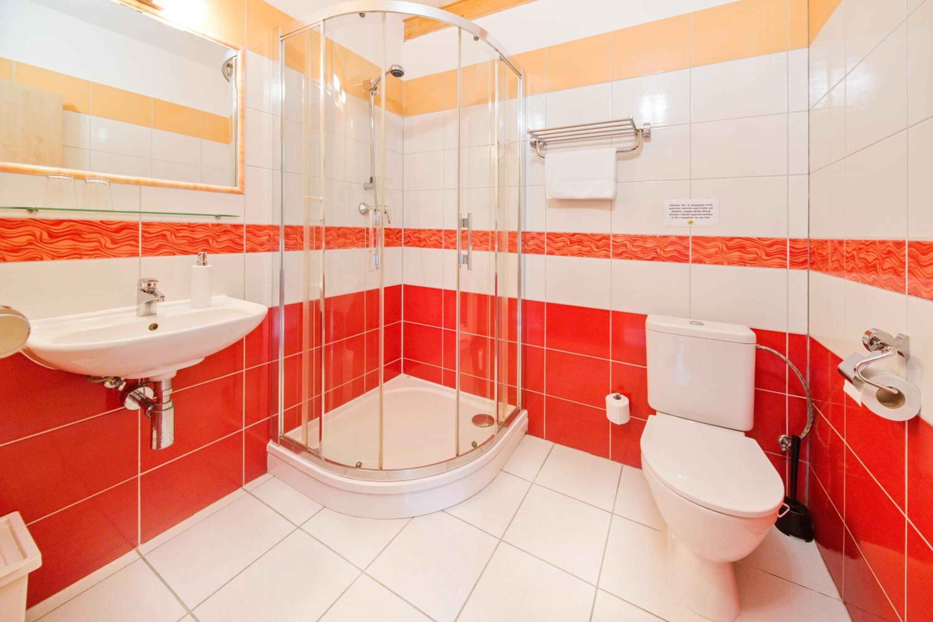A bathroom with a glass-enclosed shower, a white sink, and a toilet.
