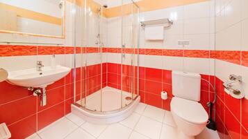 A bathroom with a glass-enclosed shower, a white sink, and a toilet.