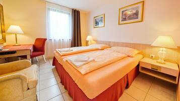 A hotel room with two beds, a desk, a chair, and two bedside tables with lamps.