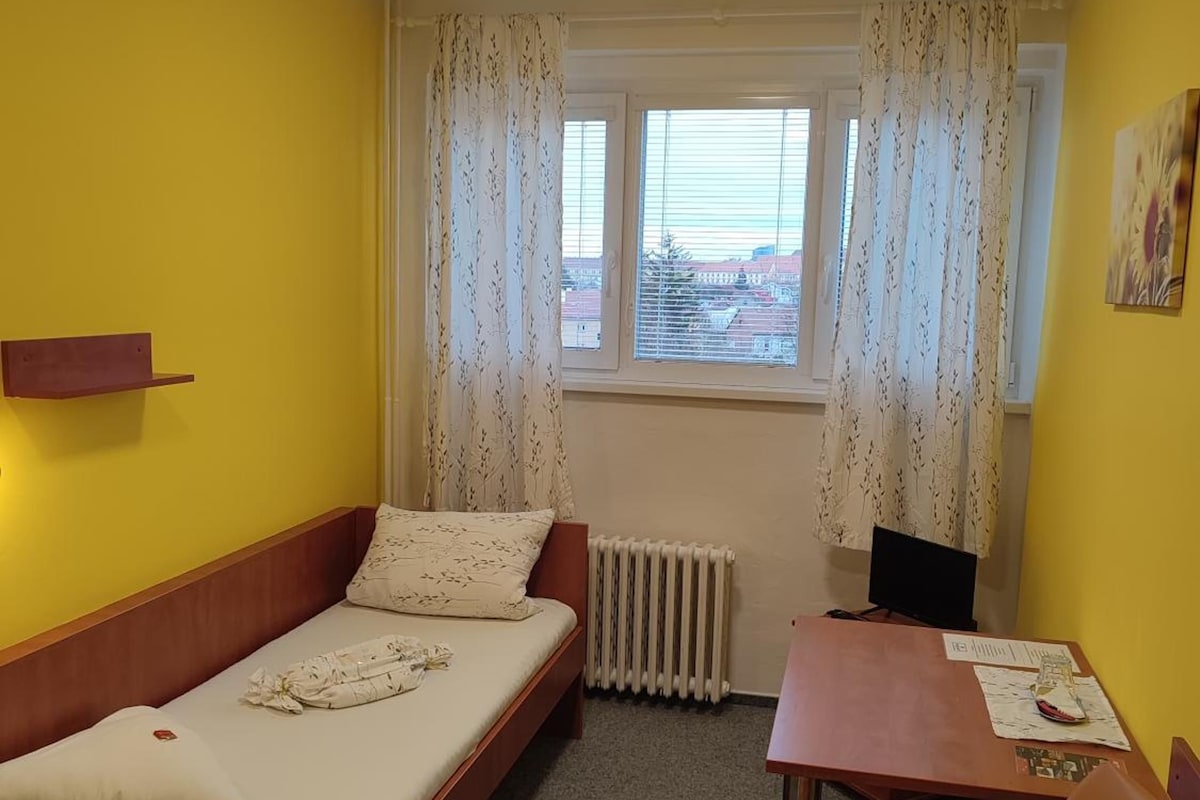 Una habitación pequeña con una cama, una mesa y una silla.