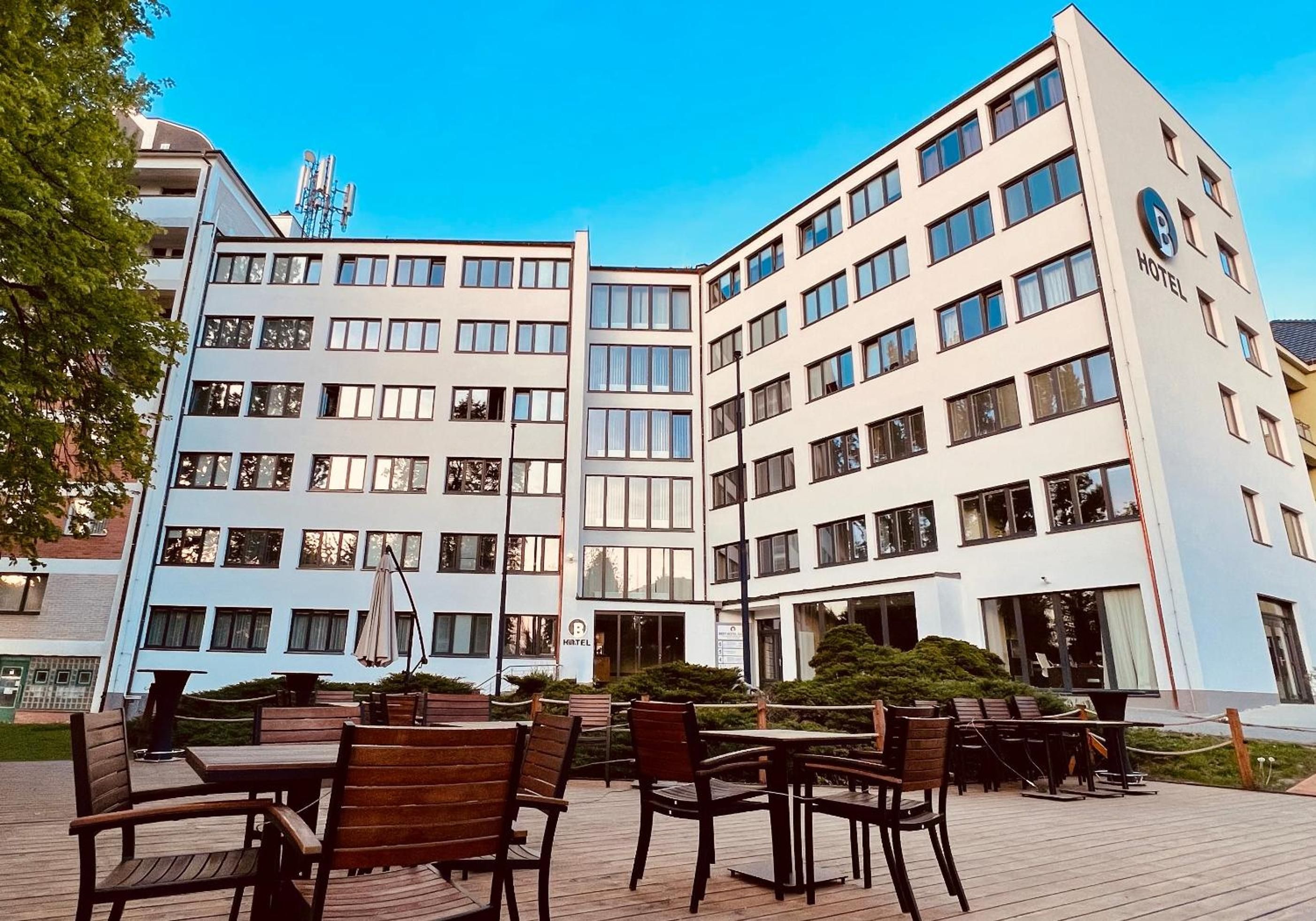 Un hotel de varios pisos, con terraza exterior y cielo despejado.