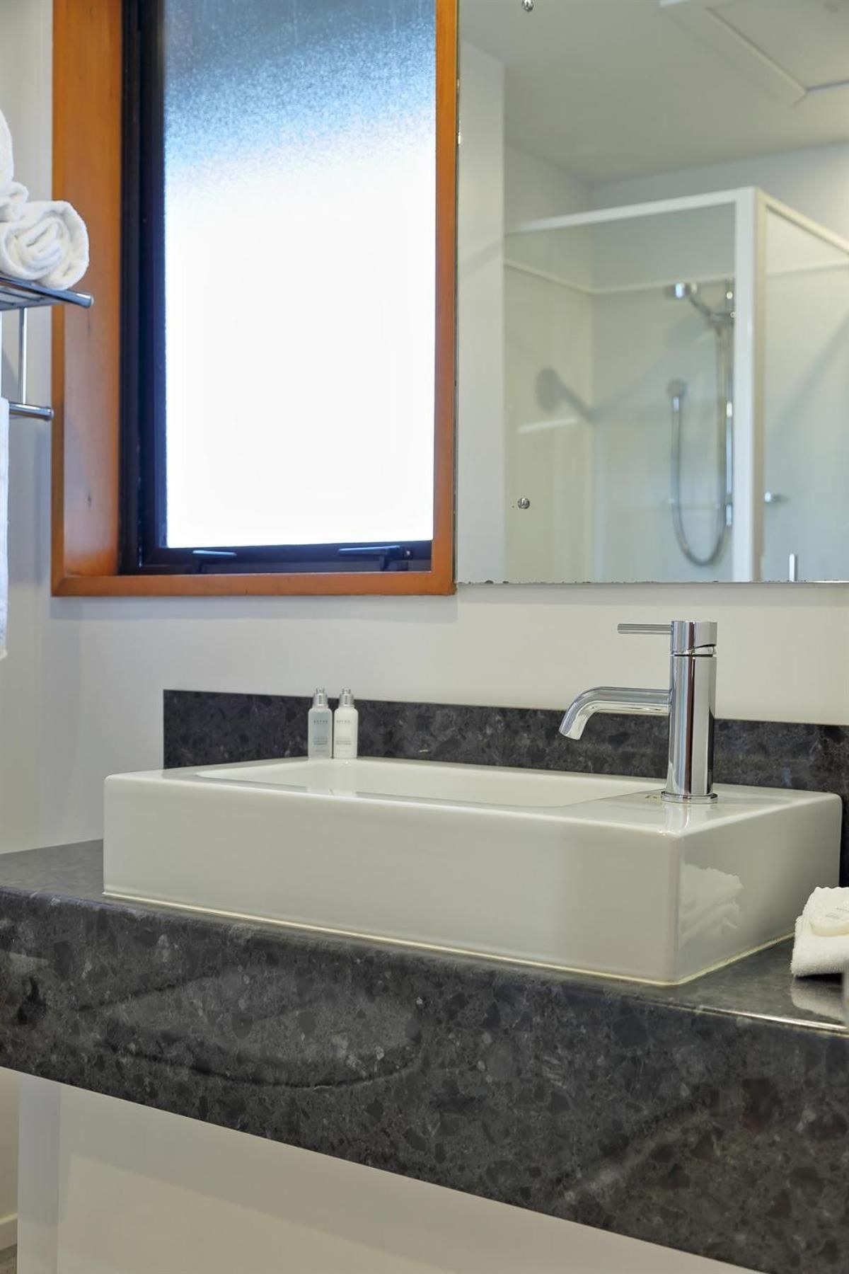 A bathroom with a white sink, a mirror, and a shower.