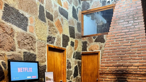 A stone-walled room with a fireplace, a television, and a couch. - Los Azufres Spa Natural (Ciudad Hidalgo)