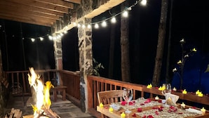 An outdoor dining area with a fire pit, string lights, and scattered rose petals on the stone floor. - Los Azufres Spa Natural (Ciudad Hidalgo)