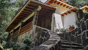 A stone staircase leading to a wooden-roofed building with a white wall and a potted plant on the right. - Los Azufres Spa Natural (Ciudad Hidalgo)