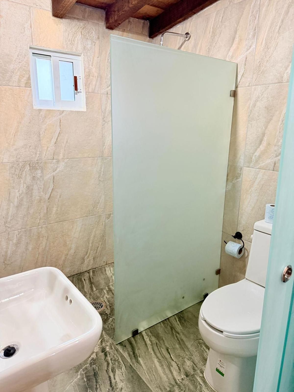 Un baño con piso de mármol, un lavamanos blanco, un inodoro y una puerta.