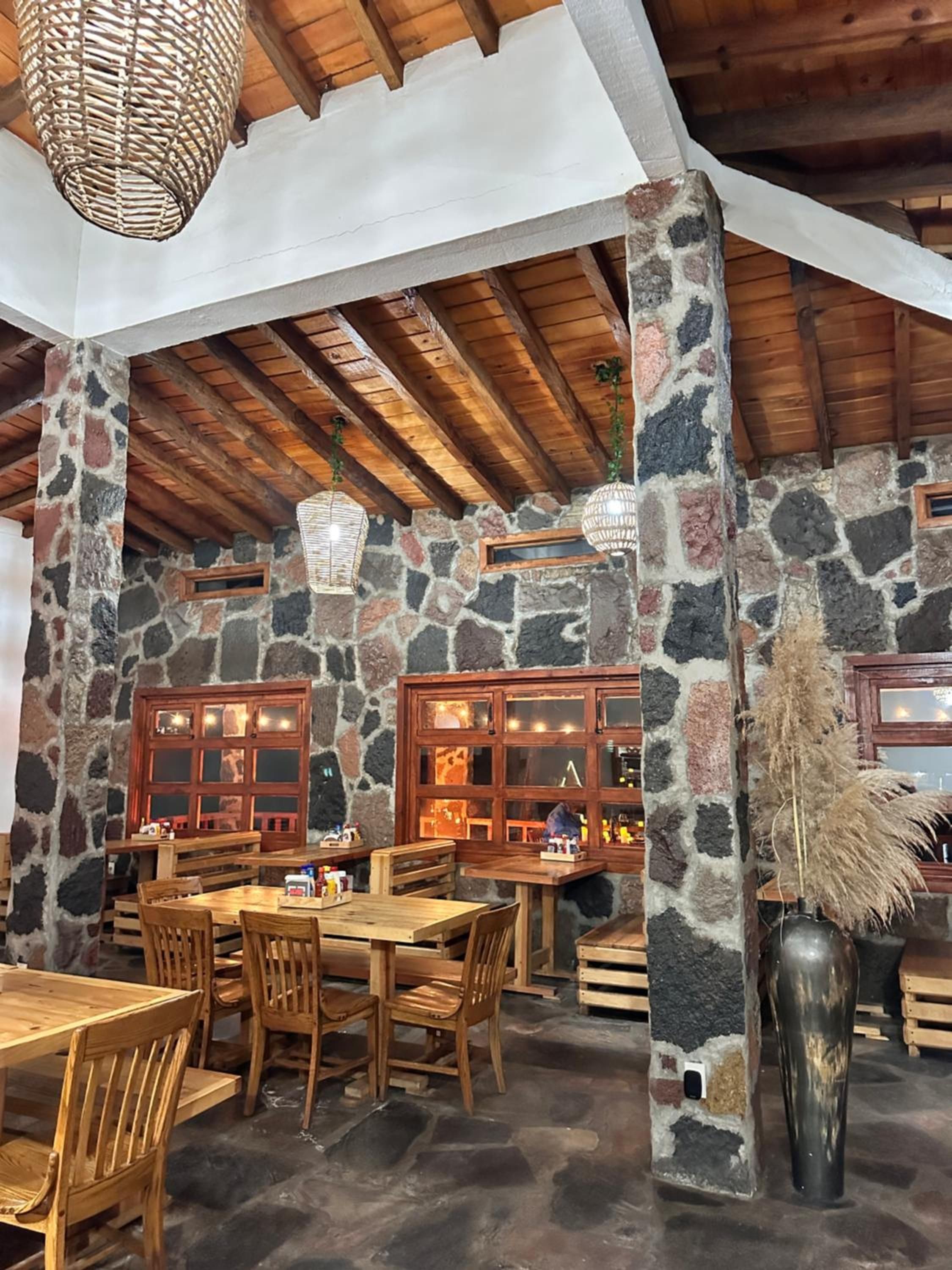 A rustic interior with stone walls, wooden beams, and a stone column with a vase.