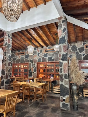 A rustic interior with stone walls, wooden beams, and a stone column with a vase.