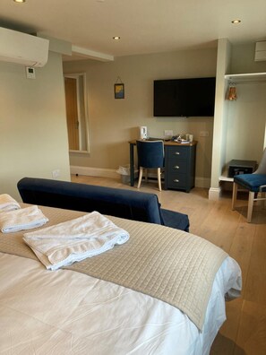 Una habitación de hotel con cama, escritorio, silla, televisor y armario.