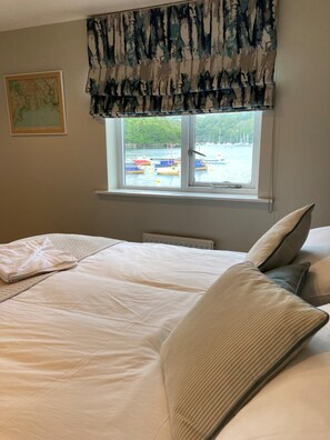 Un dormitorio con una cama grande, una ventana con vistas a barcos y un cuadro en la pared.