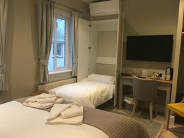 Habitación de hotel con dos camas, un escritorio, una silla, un televisor y una ventana con cortinas.