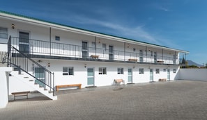 A two-story building with a covered outdoor area, a staircase, and multiple windows.