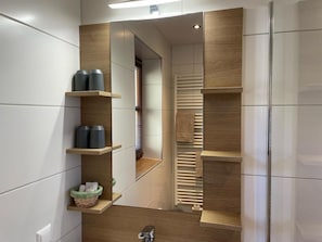Un baño moderno con un mueble estante empotrado, un perchero y una zona de ducha visible.