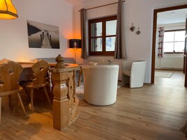 Una sala acogedora con una mesa de comedor de madera, otomanas blancas y una lámpara.
