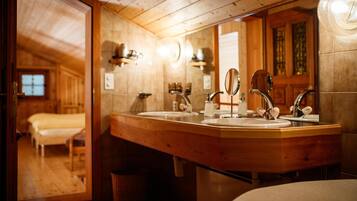 A wooden bathroom with a large mirror, two sinks, and a wooden vanity.