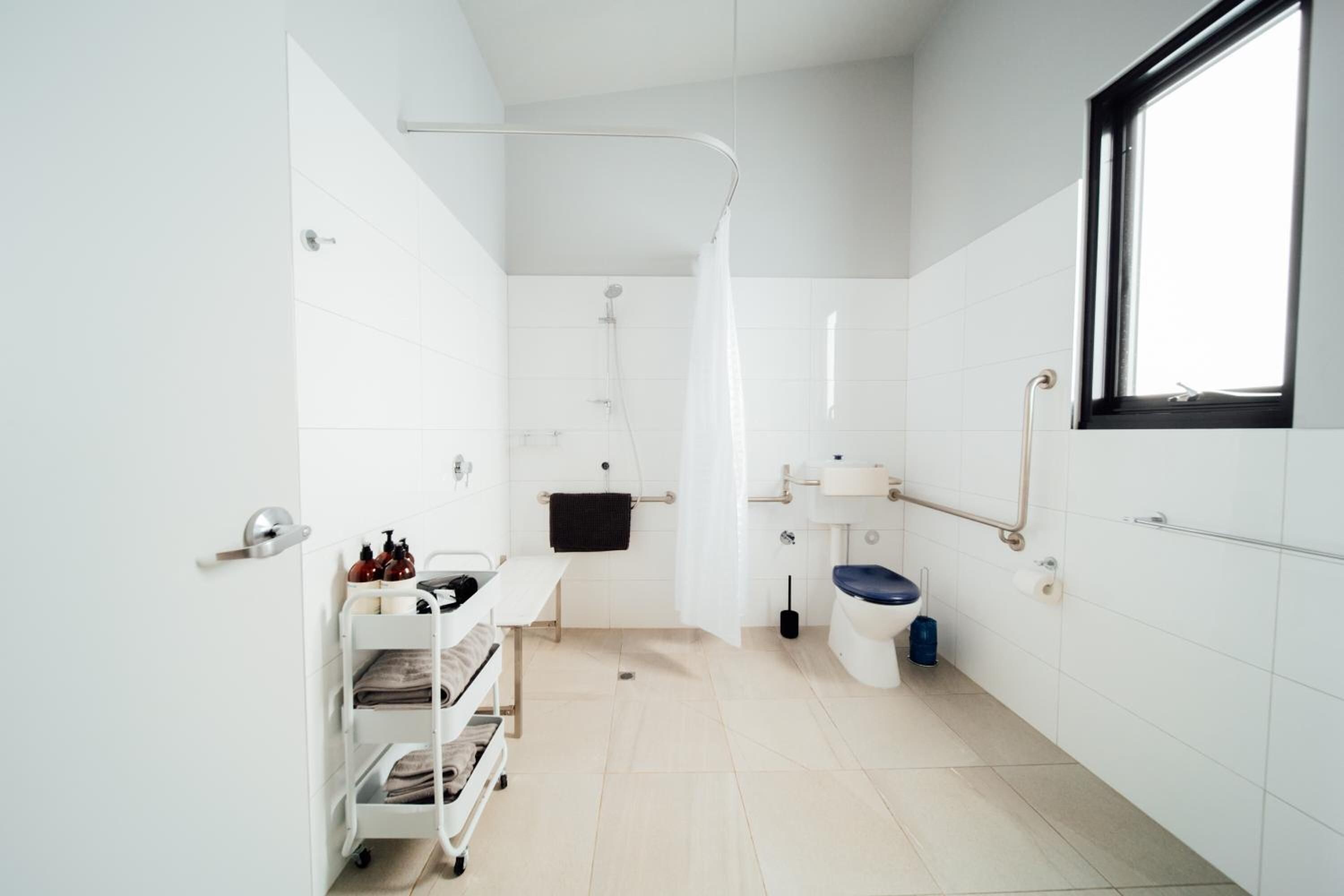 A modern bathroom with a shower, toilet, sink, and a window.