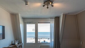 Una habitación de hotel con cama, una silla, un escritorio y vista a la playa.