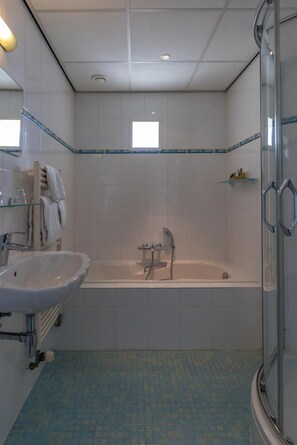 Un baño con bañera, lavabo y cabina de ducha de vidrio.