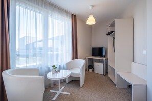 A hotel room with a bed, a TV, a desk, a chair, and a window with curtains. - Blue Label Apart House (Sofia)