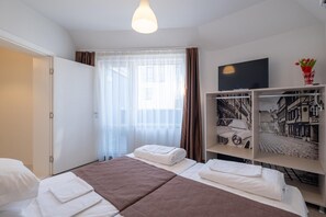 A hotel room with a bed, a TV, and a bookshelf with a cityscape photo. - Blue Label Apart House (Sofia)