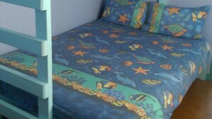 Un letto a castello con copripiumino giallo e blu, un cuscino e una coperta piegata sul letto superiore.