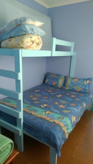 Ein Etagenbett mit einer blauen und gelben Bettdecke, einem Kopfkissen und einer zusammengelegten Decke im oberen Bett.