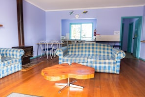 Una sala de estar con un sofá a cuadros, una mesa de centro de madera, una chimenea y un comedor con sillas y una mesa.