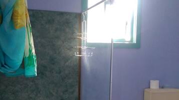 A bathroom with a shower, a toilet, and a window.
