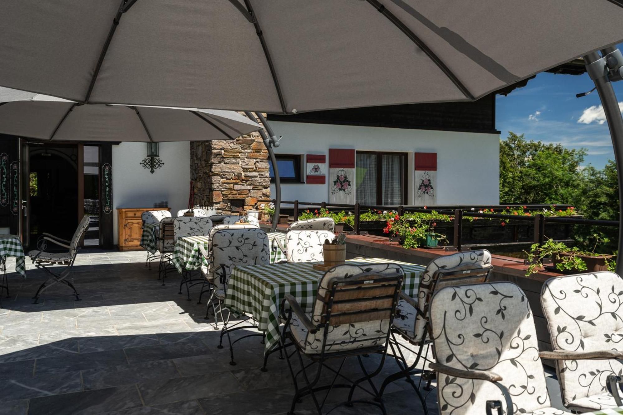 Eine Außenpatio mit Tischen und Stühlen, eine Steinmauer und Blick auf ein Gebäude mit Fenstern und einem Balkon.
