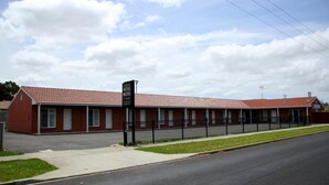 A motel with a red-tiled roof, a black fence, and a sign indicating vacancies. - Allansford Hotel Motel (Allansford)