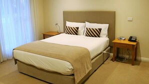 A hotel room with a large bed, a bedside table with a phone, and a lamp. - Allansford Hotel Motel (Allansford)