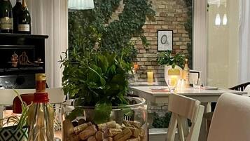 A dining area with a table set for two, featuring a bottle of Pepsi, a glass, a plate, and a bowl of wine corks.